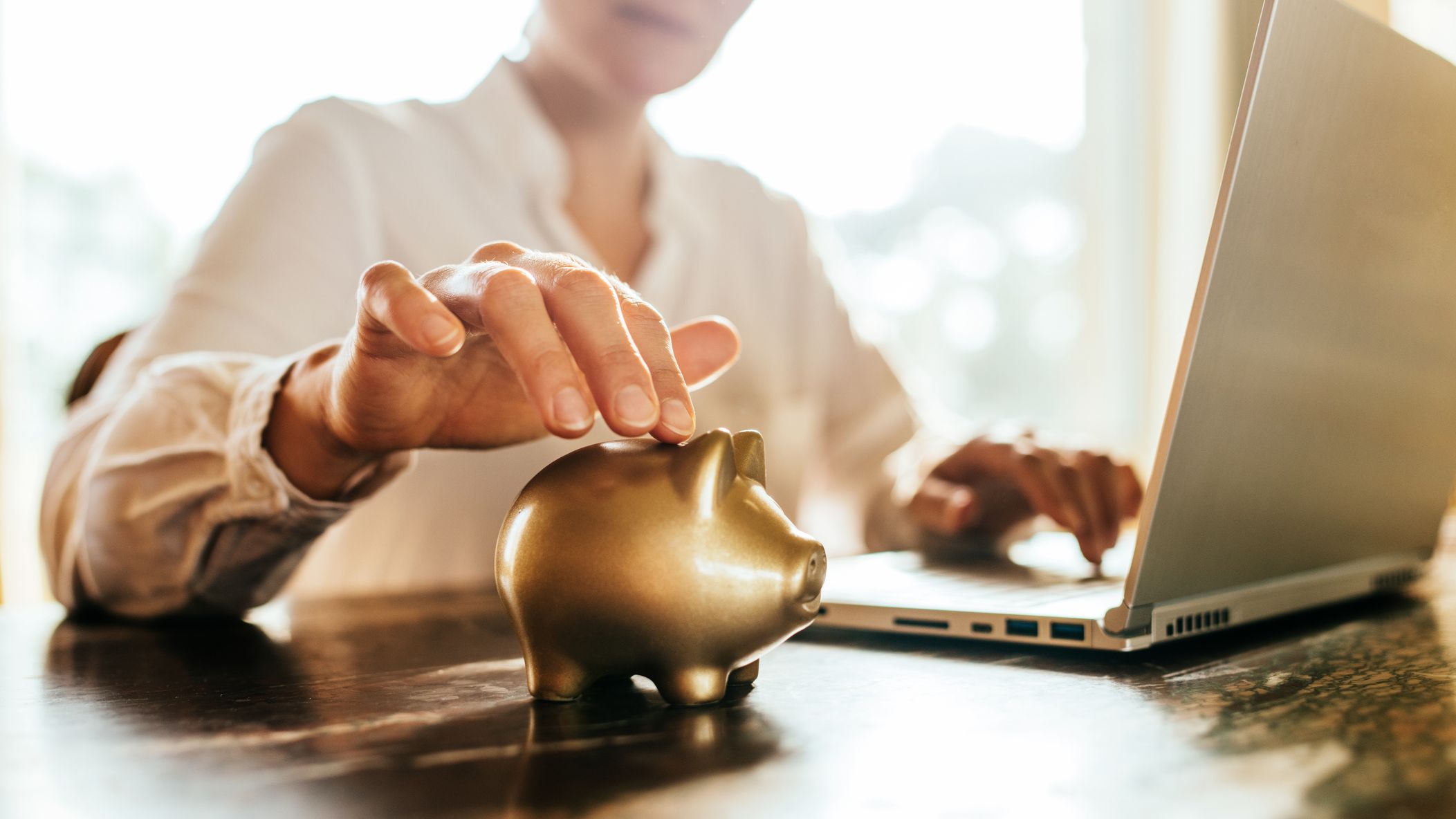an older woman putting money into a gold piggy bank