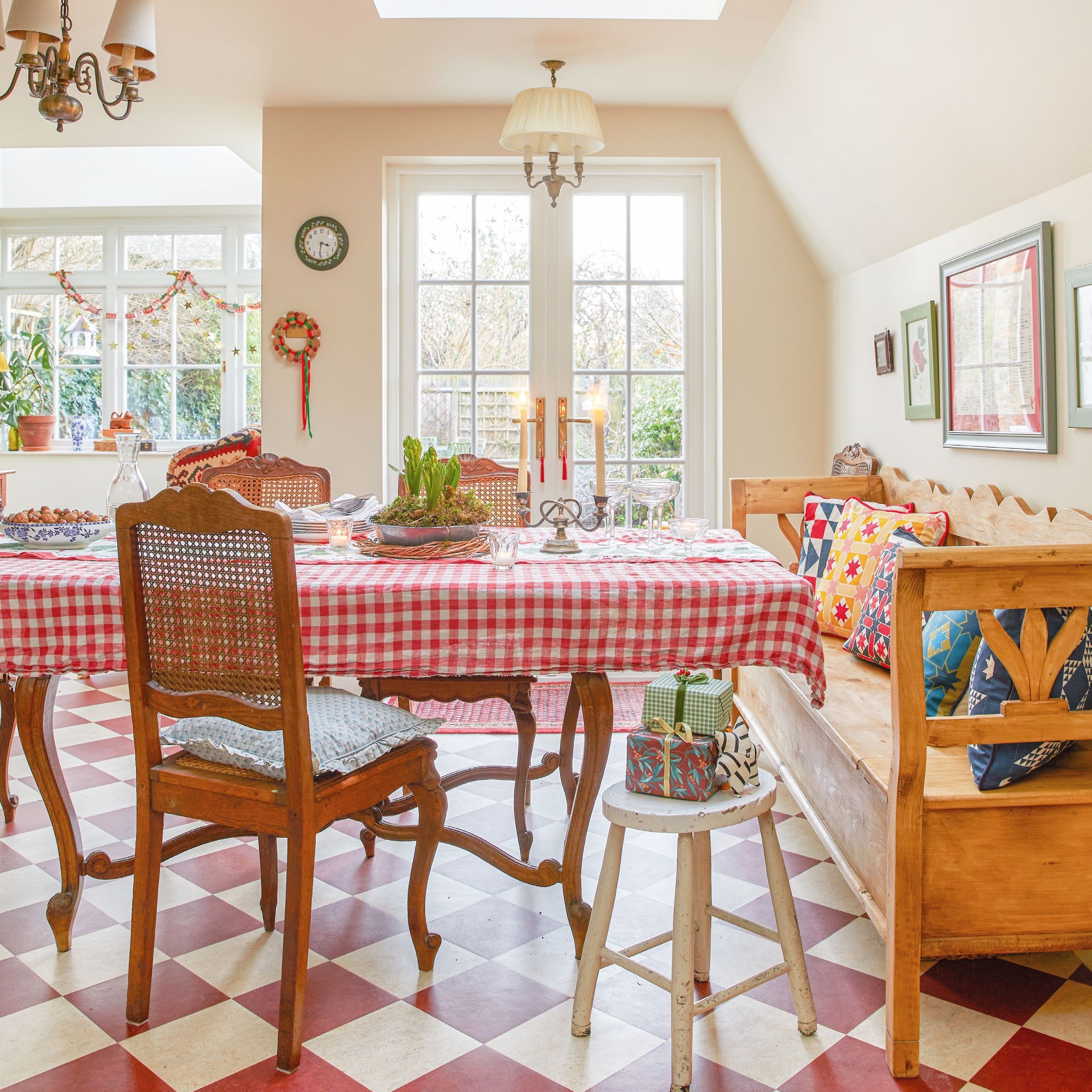 table laid with gingham cloth and candles, with antique chairs and a wooden bench