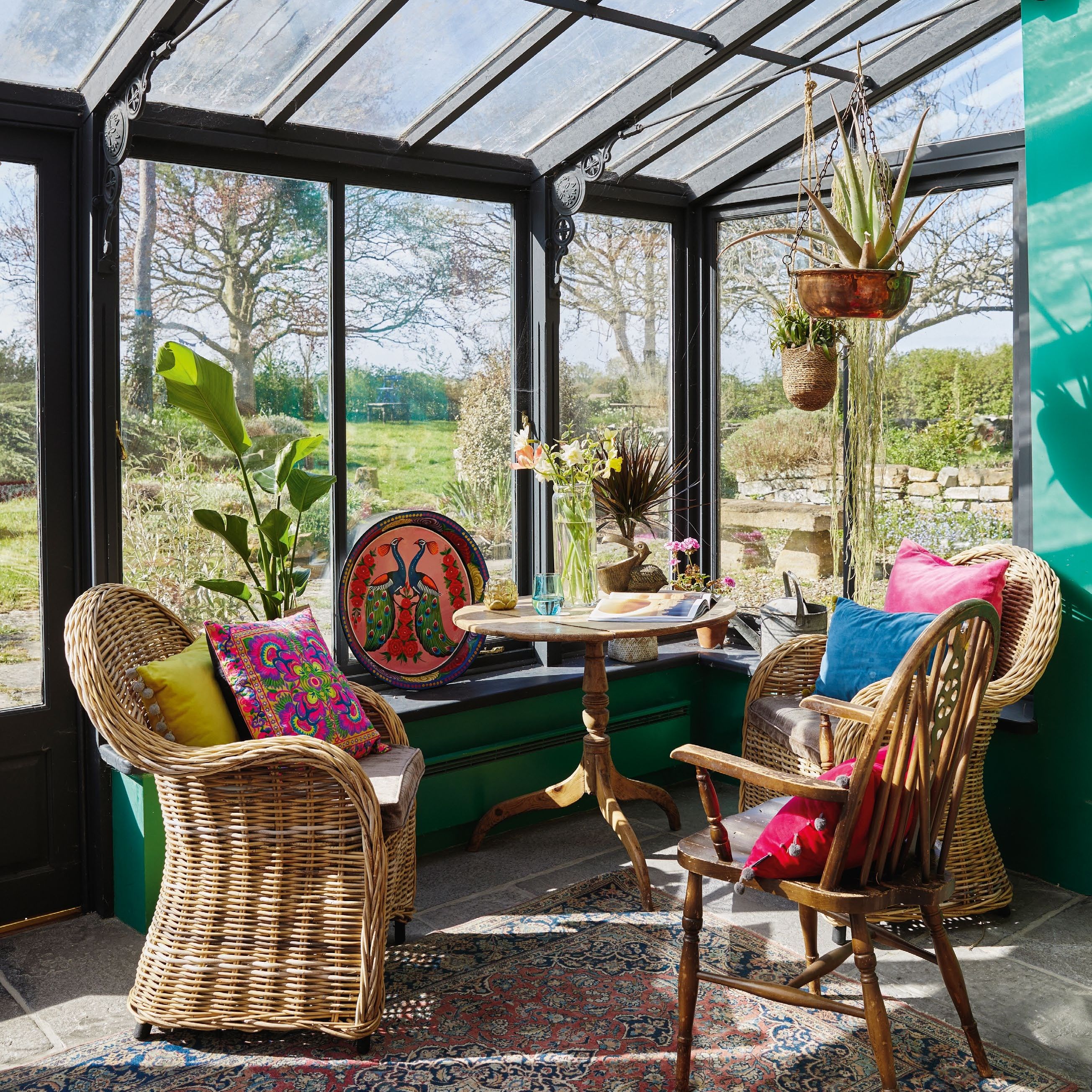 conservatory with black painted fram and mix of wicker and antique chairs