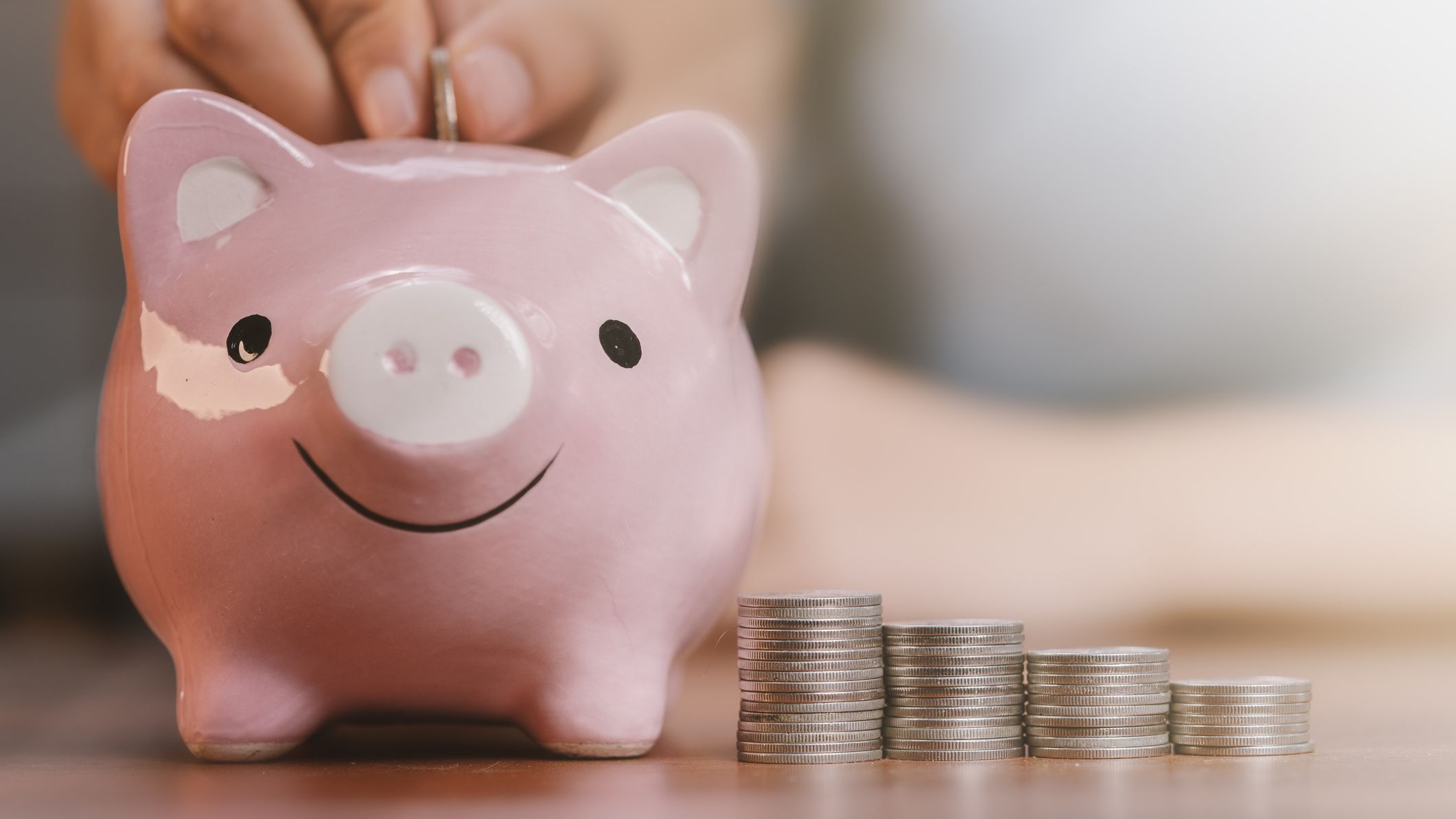 a smiling piggy bank next to a stack of coins