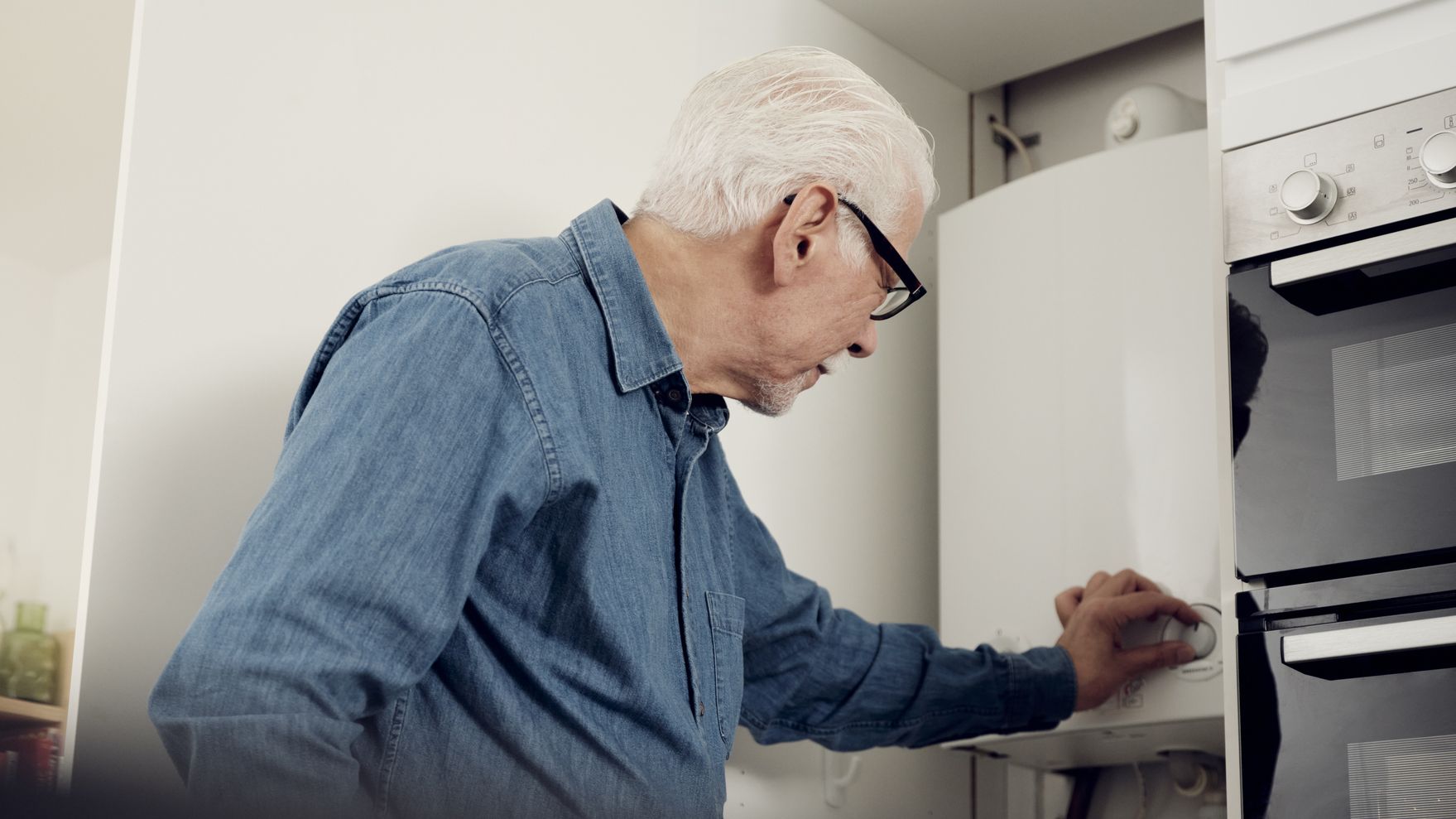 Senior man adjusting water heater for energy saving at home
