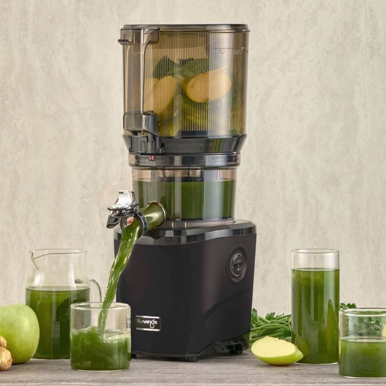 Black Kuvings juicer on countertop with green fruit and vegetables