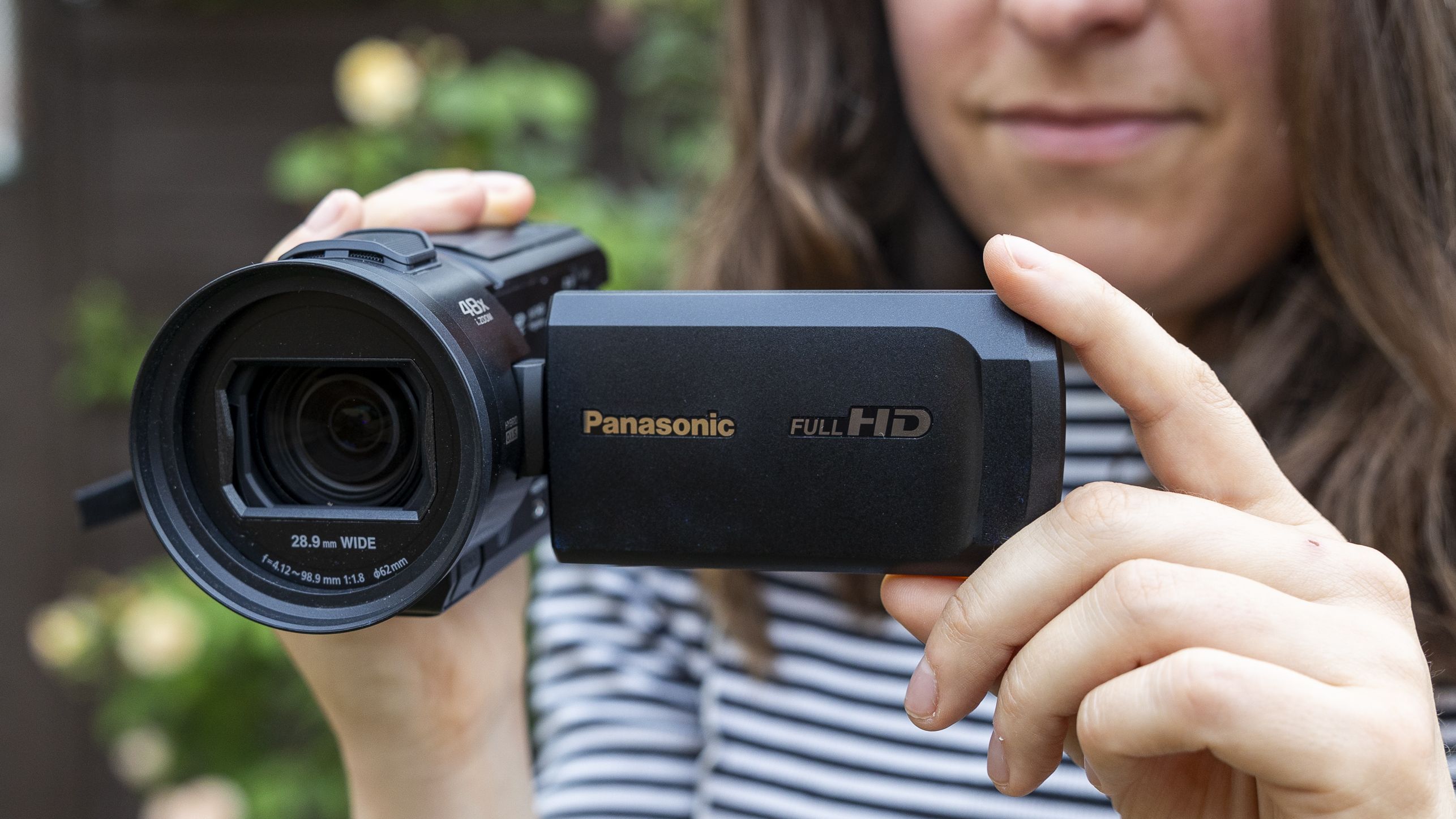 A female photographer holding the Panasonic HC-V900 in a garden