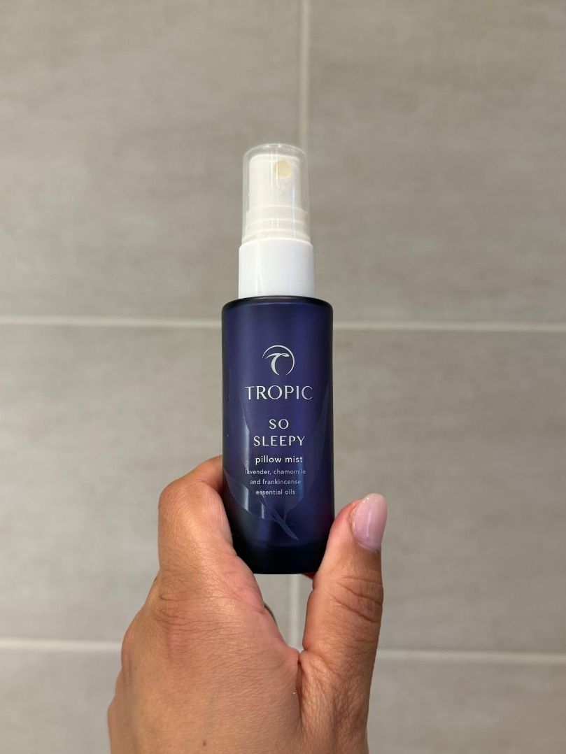 Aleesha holding empty Tropic So Sleepy Pillow Mist