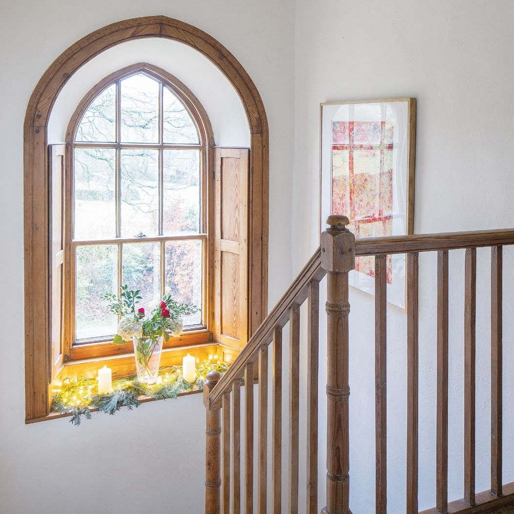 Arched wooden window on a stairwell with wooden bannisters