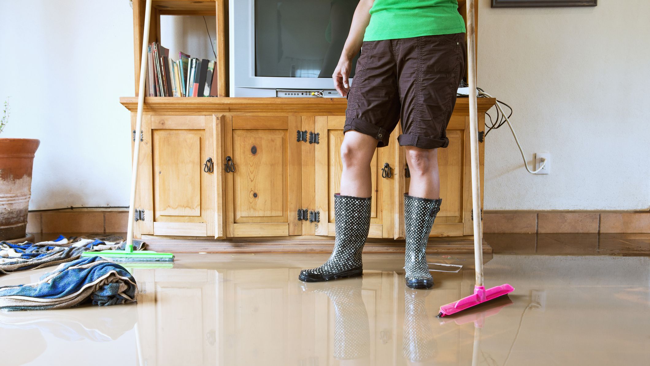 A woman cleaning up flood water in a living room.