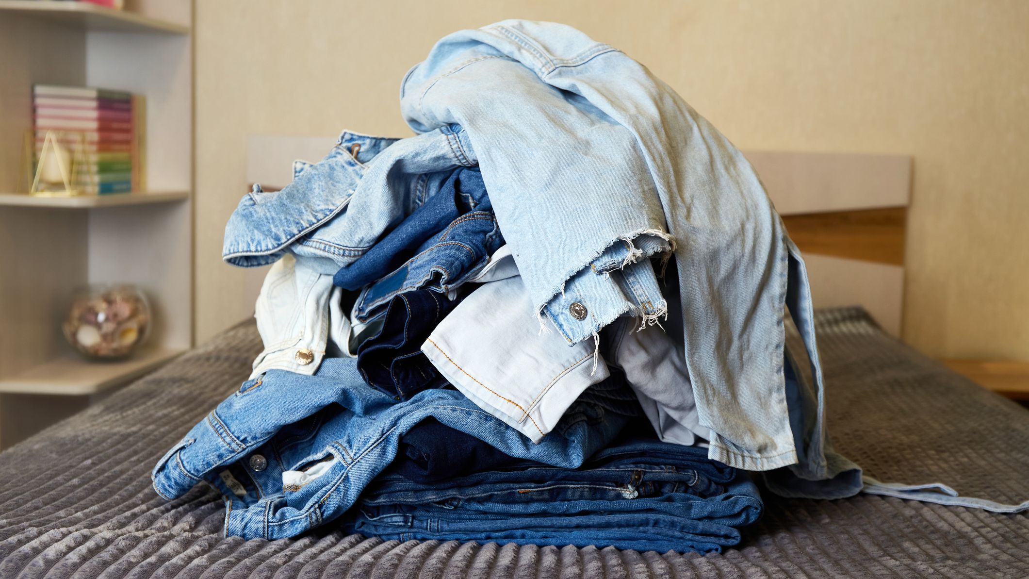 A pile of denim clothes on the bed.