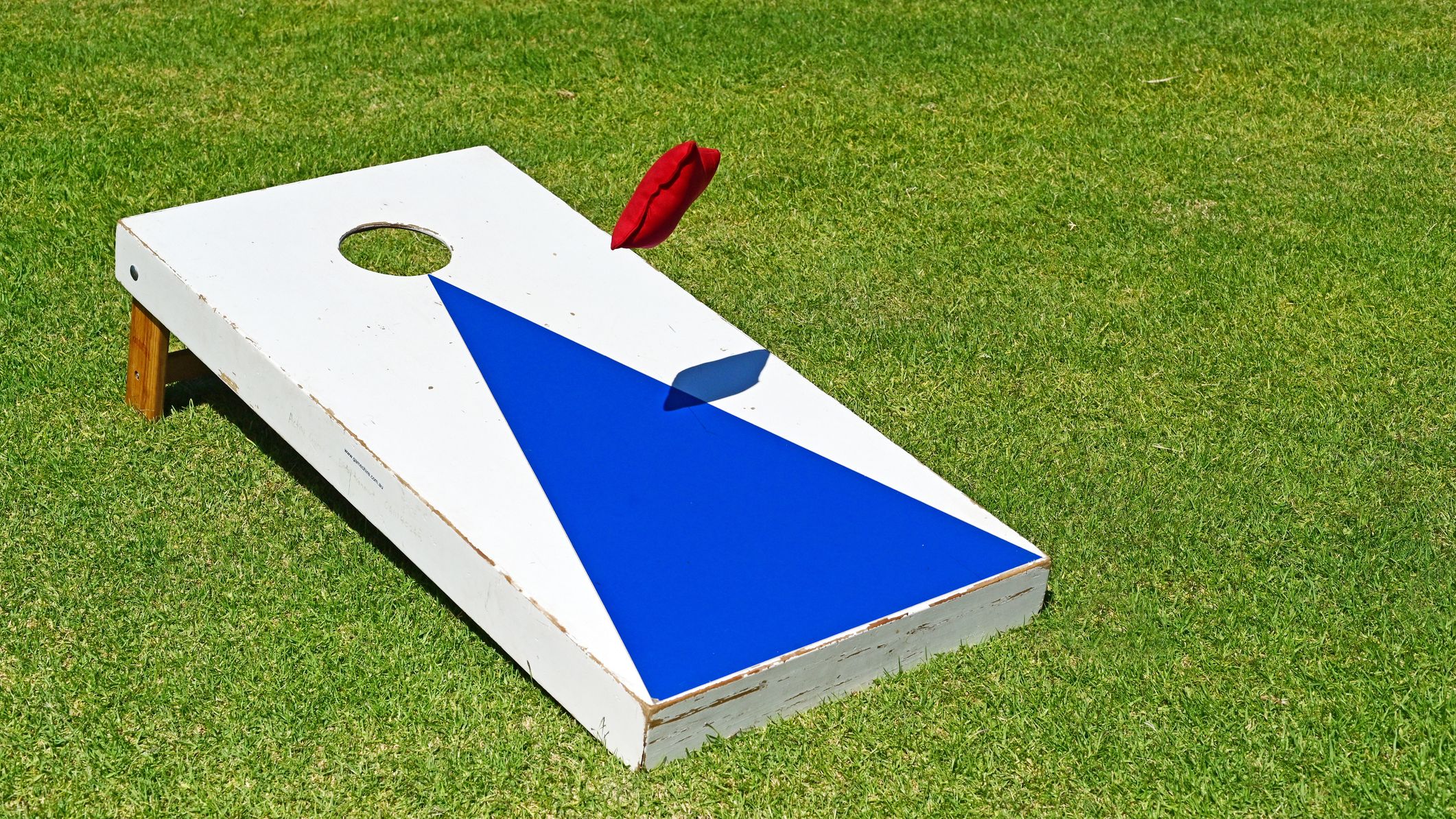 A bag thrown towards a cornhole board.
