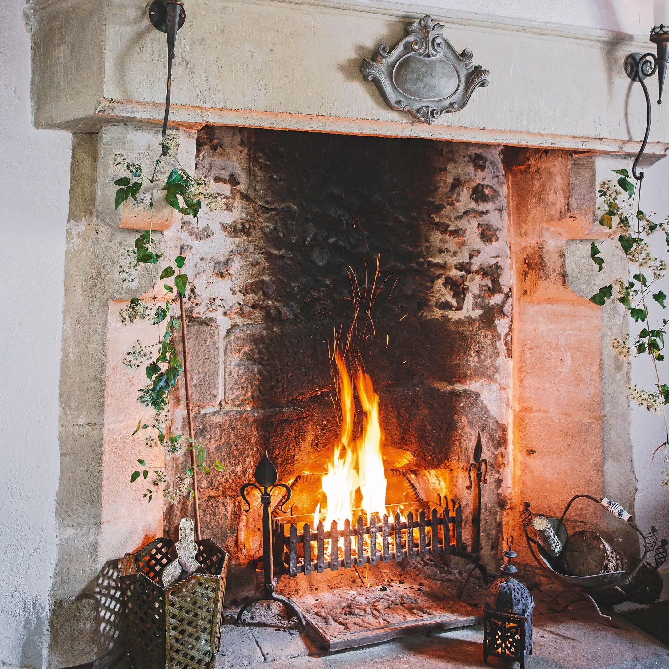 original stone inglenook fireplace with candle sconces attached to the mantel