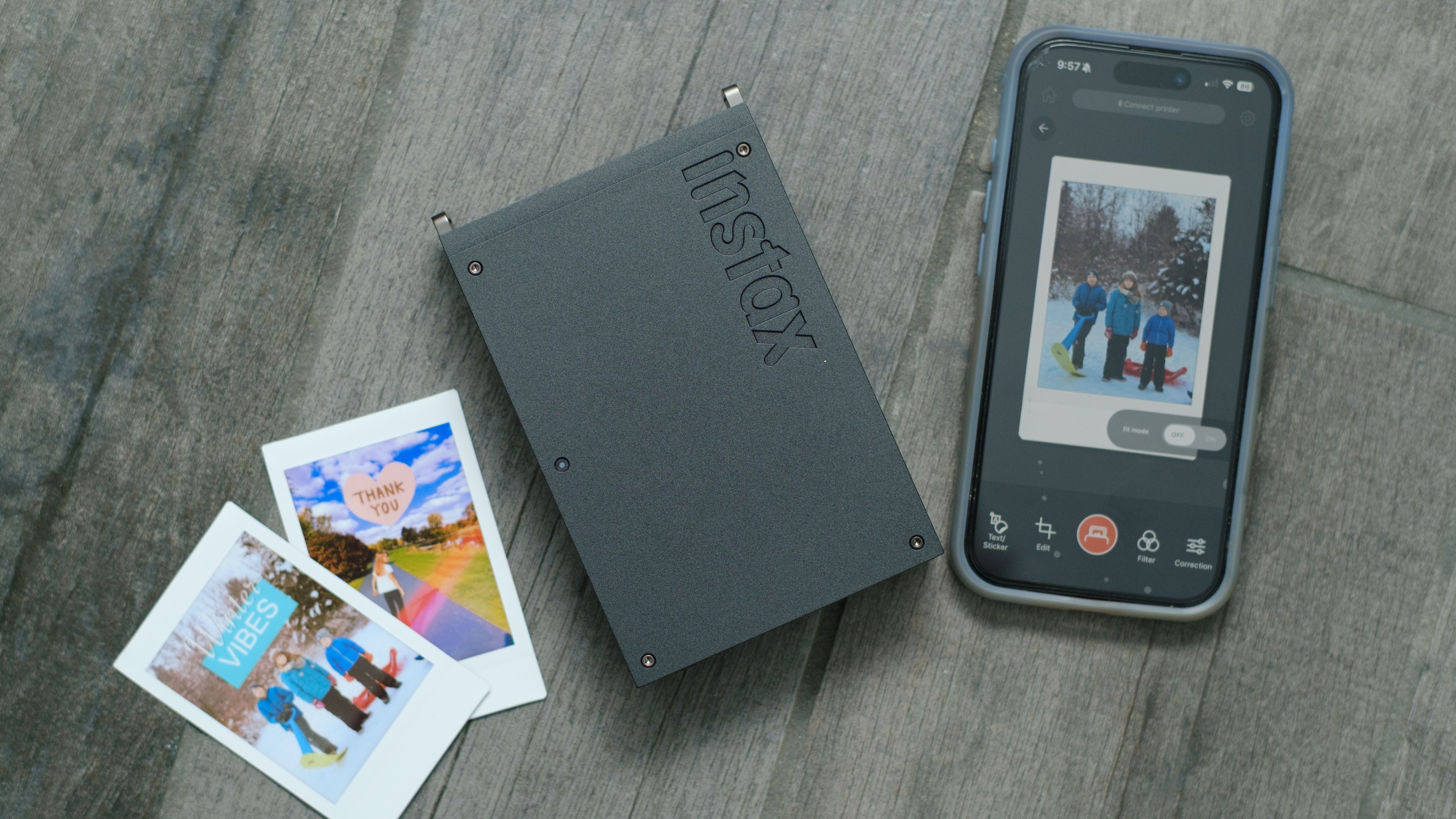 The Fujifilm Instax Mini Link+ on a gray background with instant prints