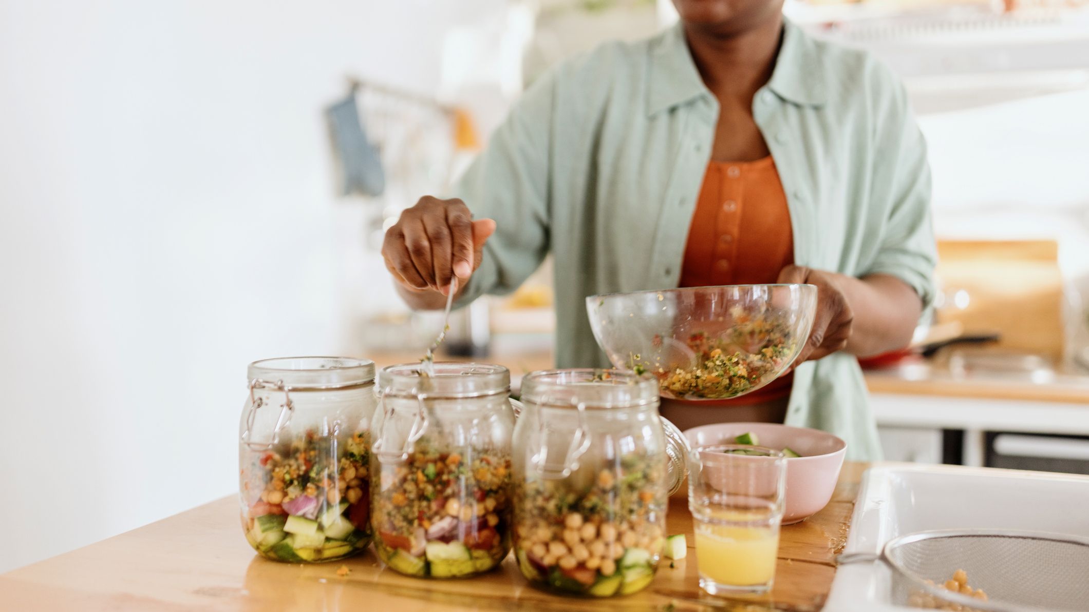 Woman filling up jars with ingredients in a kitchen