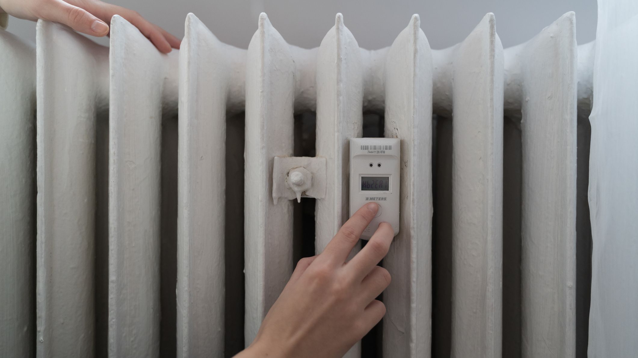 a woman sets the temperature on her electric heater