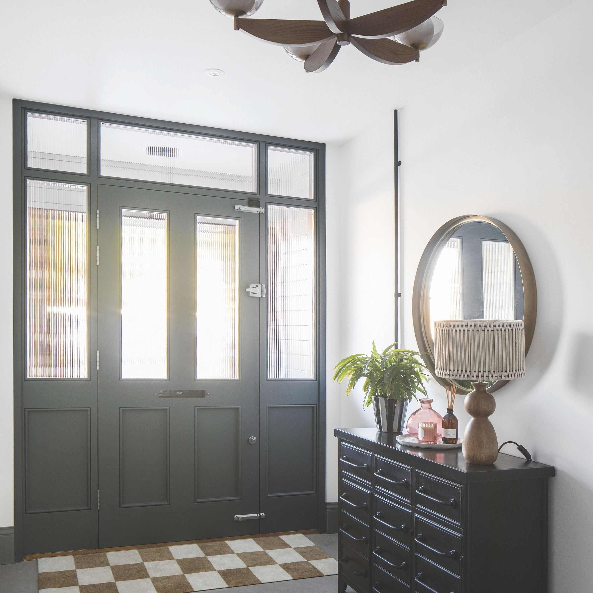 Hallway with crittall-style door, black chest, mirror, and checkered doormat