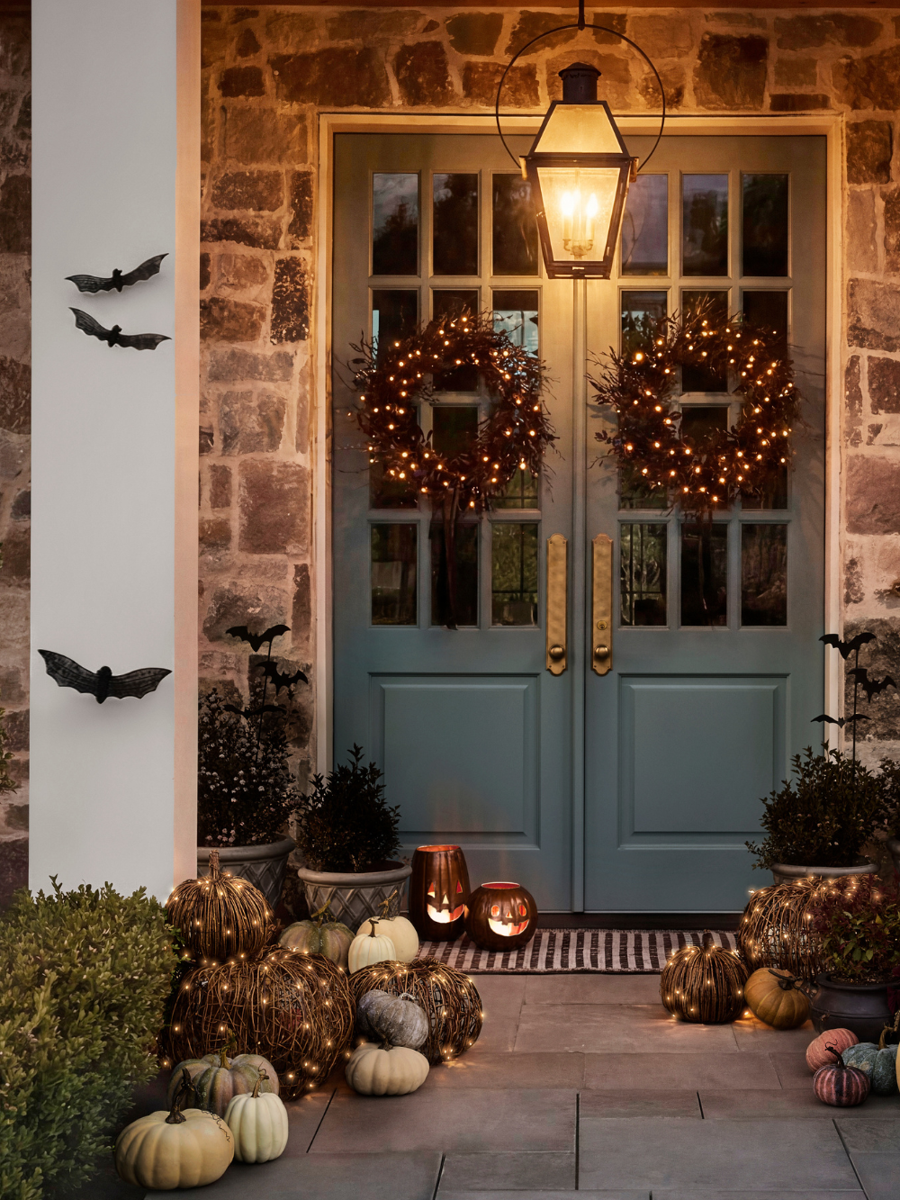 Charming entryway decorated for Halloween with wicker bat wall hangings, scattered pumpkins, and gothic wreaths