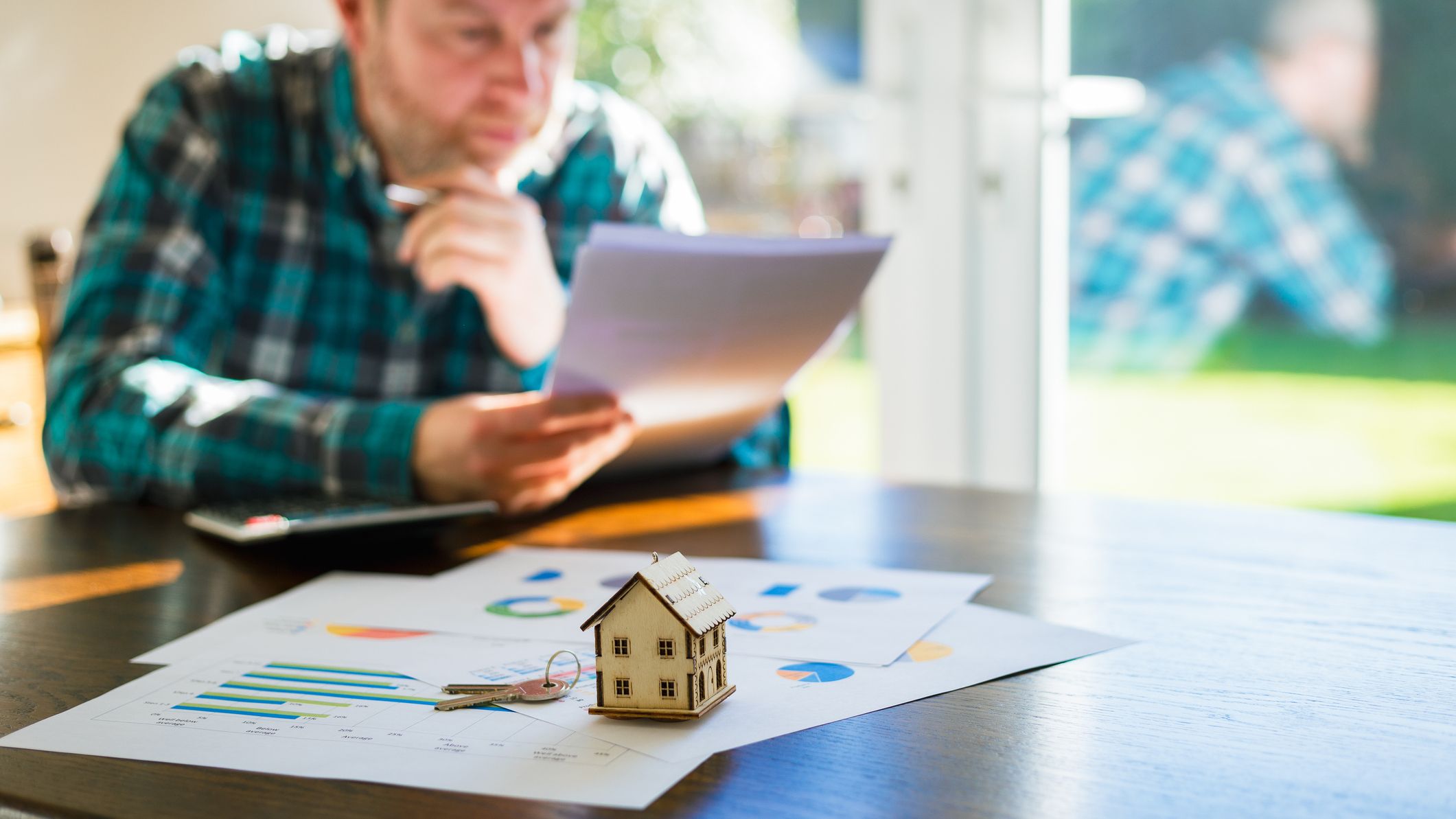 A man is looking at documents pertaining to a house sale agreement.