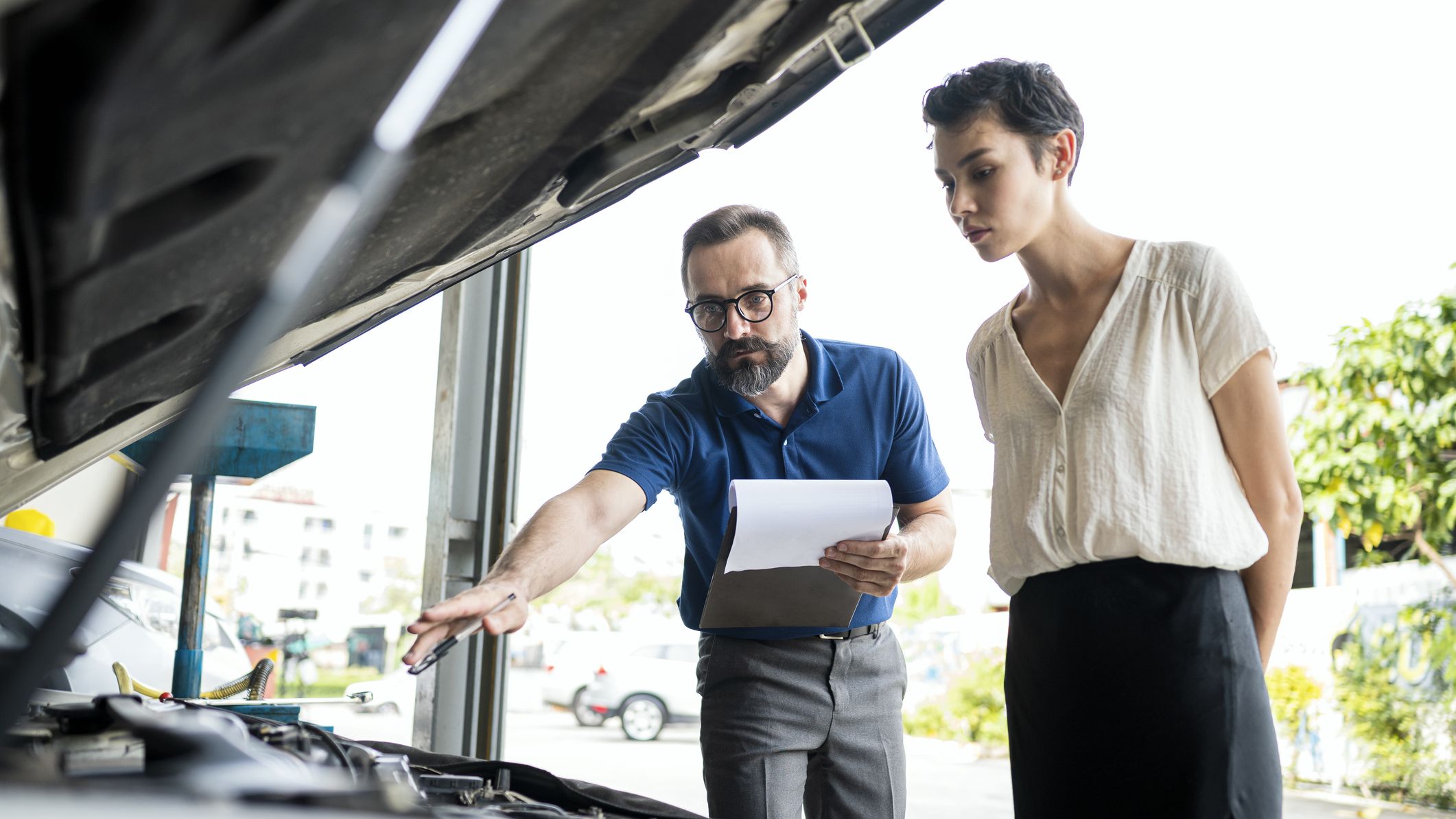 A mechanic explaining a car repair report to his female customer