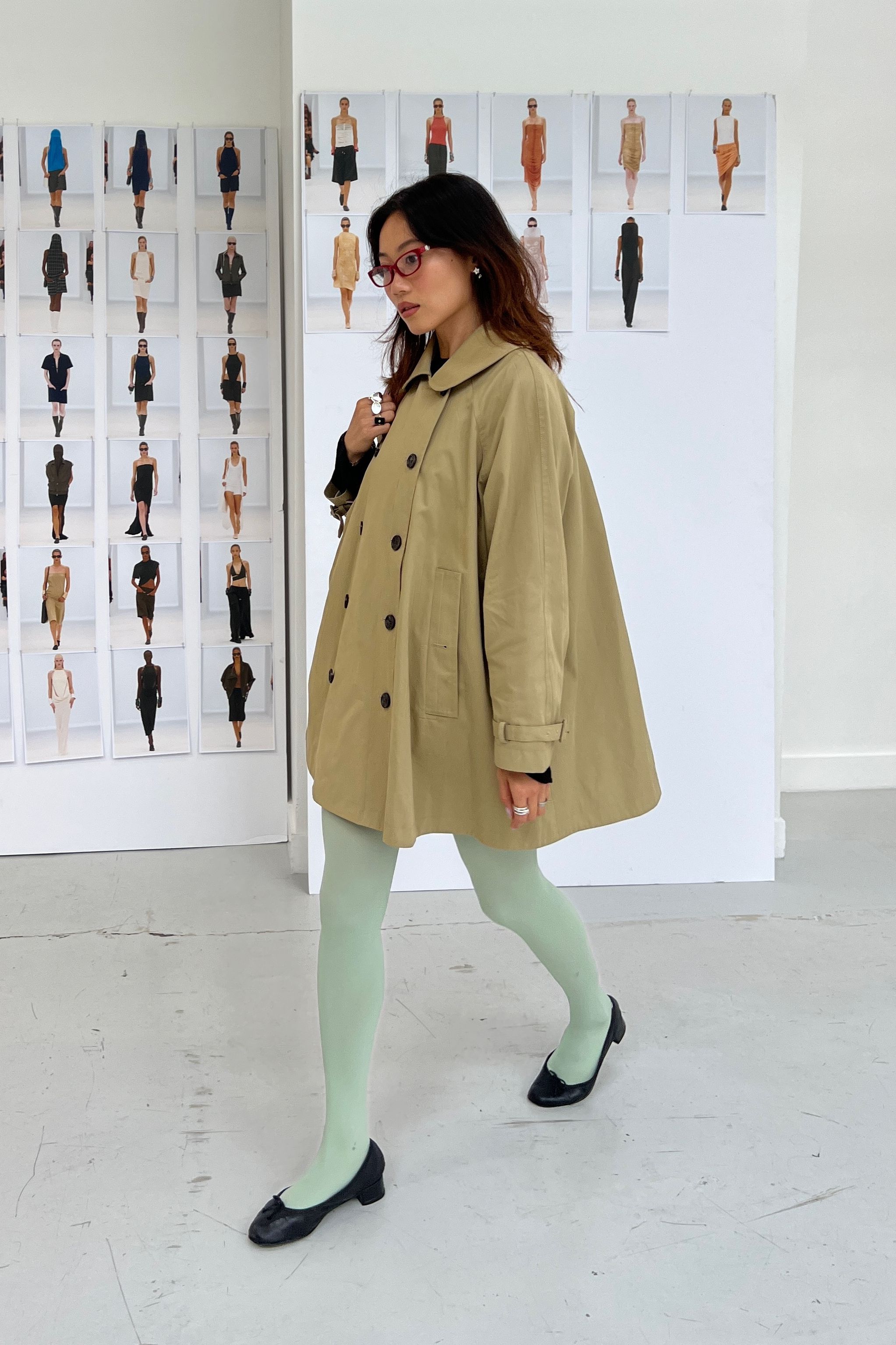 Vivian Li wearing a khaki trench coat and sea foam green colorful tights at Paris Fashion Week.
