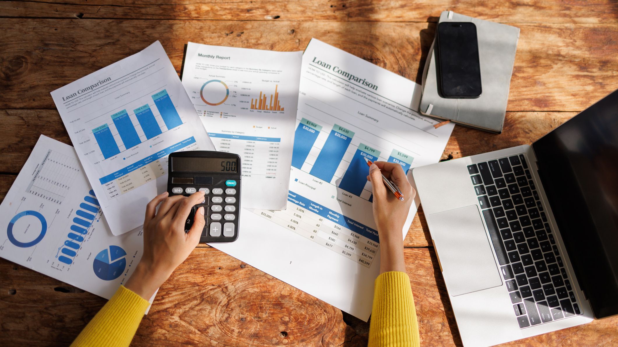 Person calculating loan comparison data using calculator and laptop