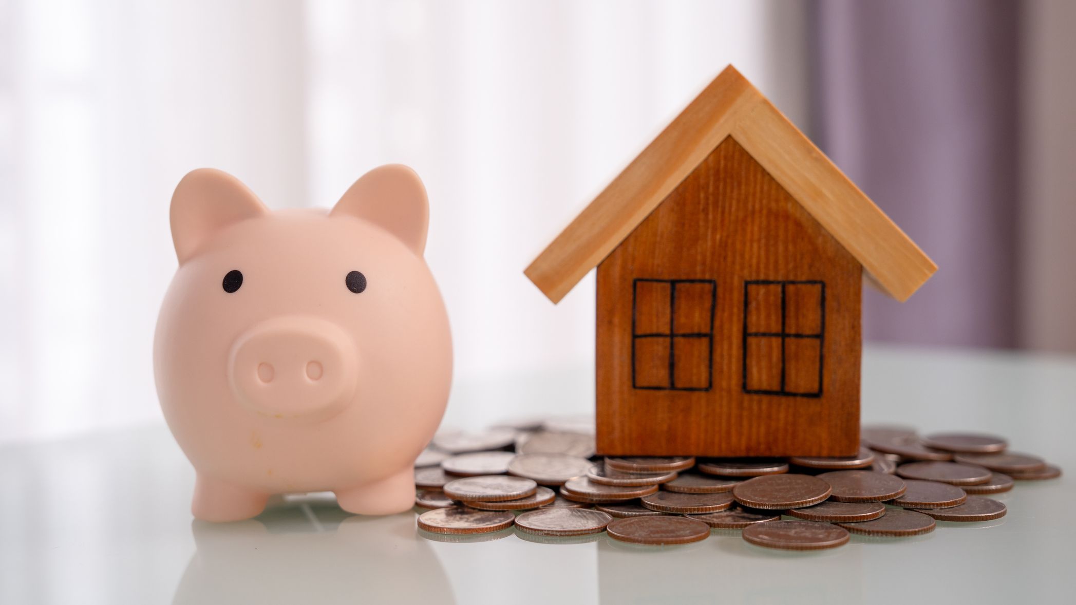 Piggy bank and stacked coins on white wooden table. Real estate investment.