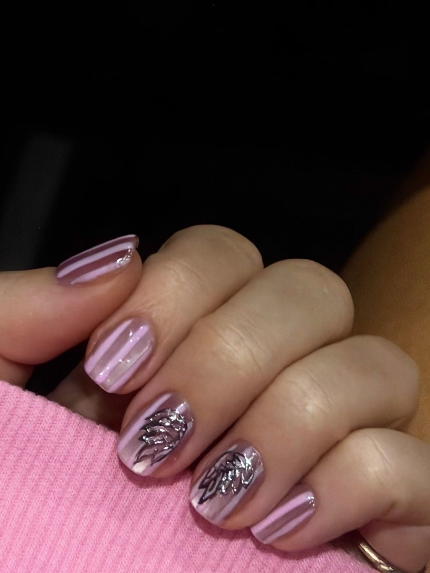 pink nails with silver angel wings on two fingers and thin pink stripes on the others