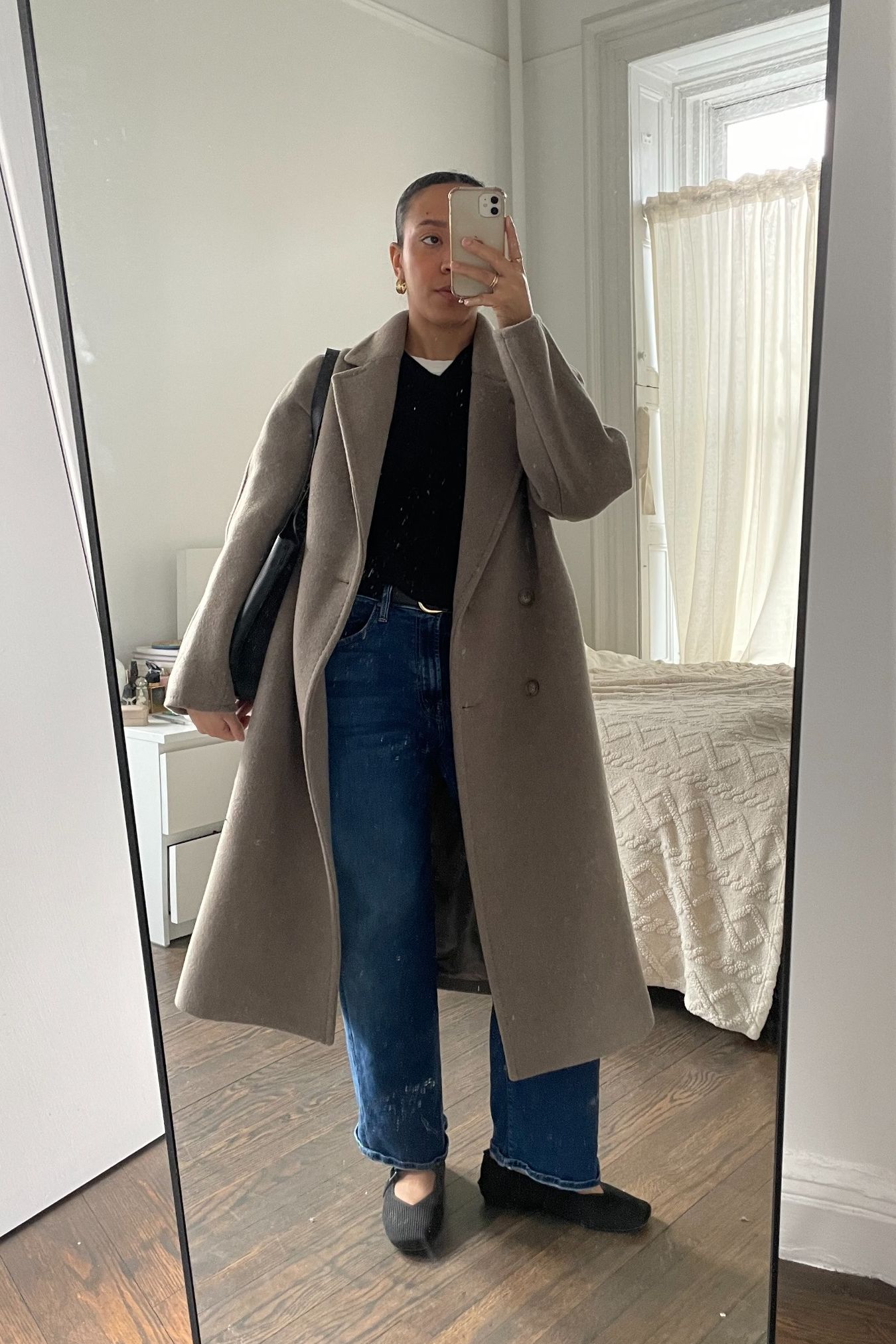 Lauren Tappan wearing straight-leg denim, a coat, a sweater, and ballet flats