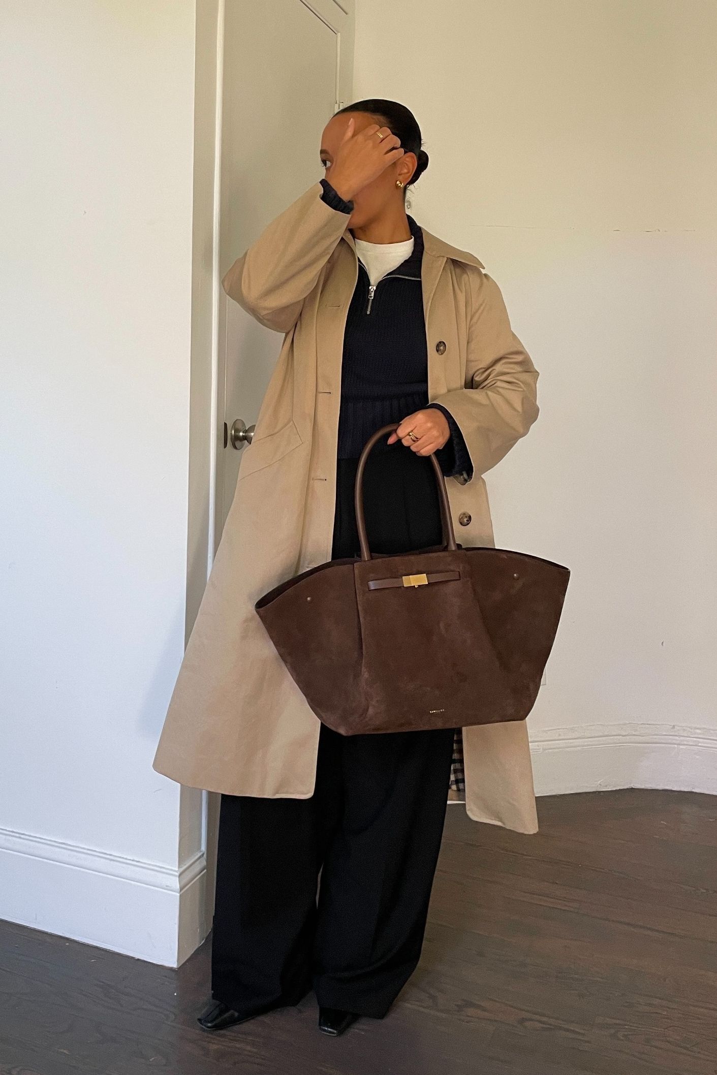 Lauren Tappan wearing a DeMellier bag, a trench coat, a sweater, and trousers