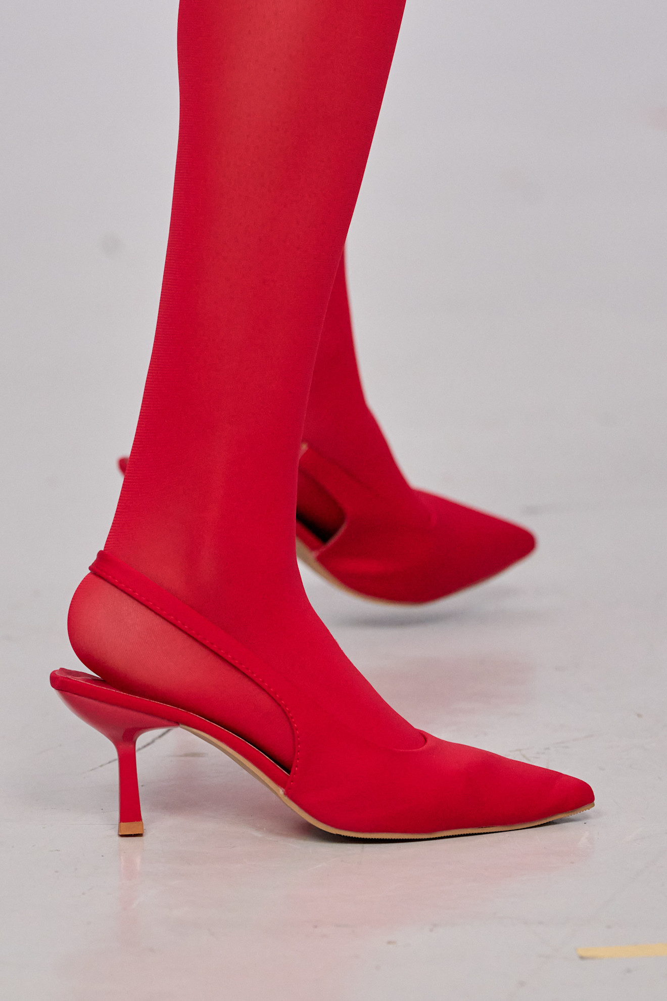 An image of the autumn/winter 2025 Chocheng runway. The model wears he winter shoe colour trend of red heels and finishes the look with red tights.