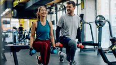 Athletic couple weight training in lunge position at health club. 