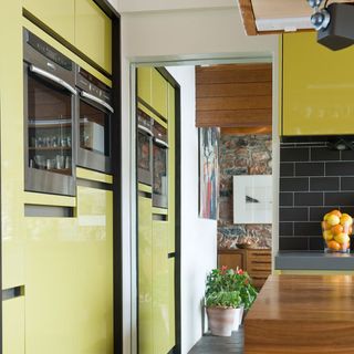 kitchen area with yellow cabinet and oven bank