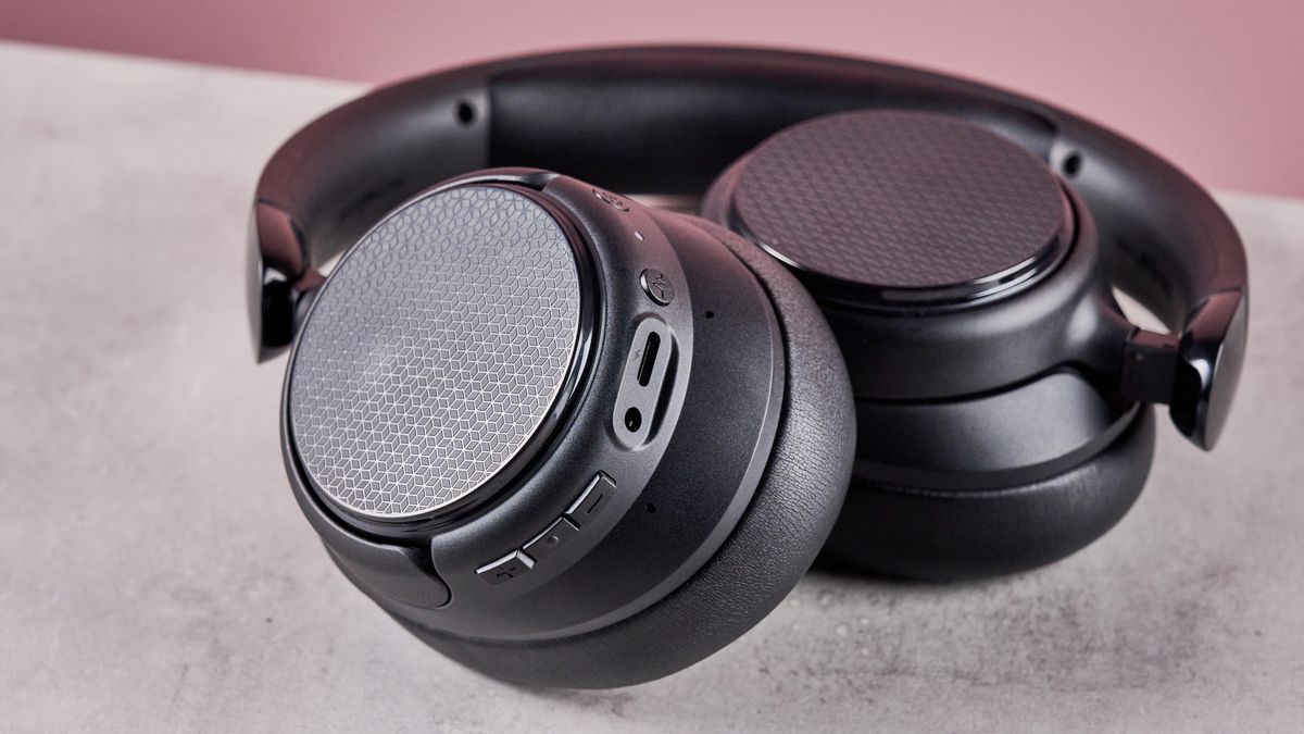 Amazon Basics Hybrid Active Noise Cancelling Headphones on a gray surface, with a pink background showing the controls on the earcup
