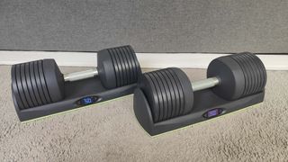 a pair of JaxJox DumbbellConnect adjustable dumbbells placed on a carpeted floor