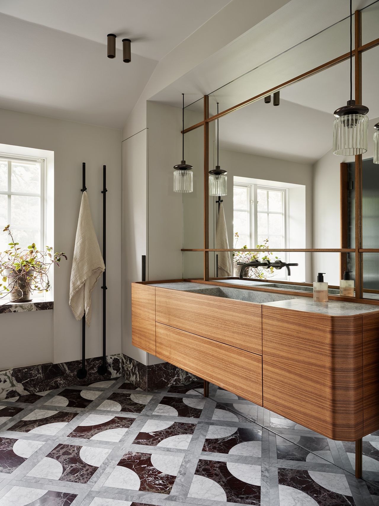 marble bathroom with mixed marble on floor creating pattern, floating timber vanity, and large mirror