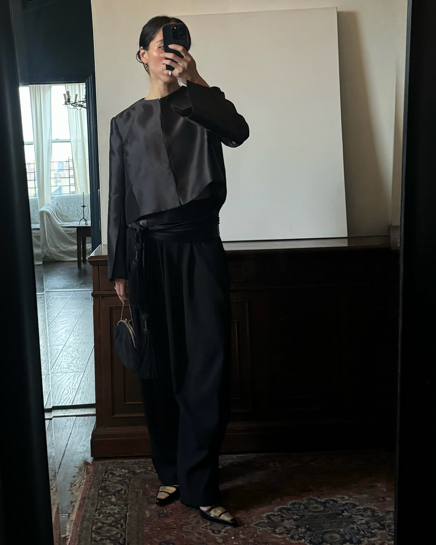 Alexis Badiyi wearing a black silk jacket with black trousers and a long silk fringe scarf.