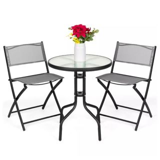 An black bistro table with fabric chairs and a glass table