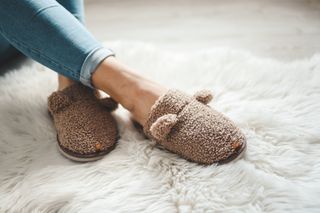 A person wearing fluffy, grey slippers.