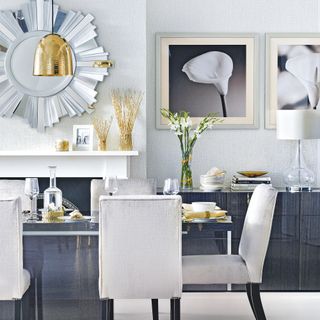 Glam white dining room with statement sunburst mirror above the fireplace