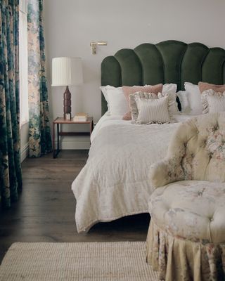 A bed with green velvet headboard and a modern sidetable