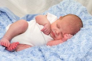 A newborn baby boy lies on a blue blanket