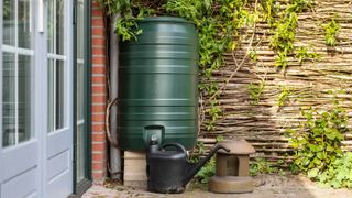 A rain barrel next to a watering can