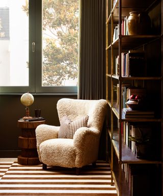 A white boucle chair in the corner of a home library