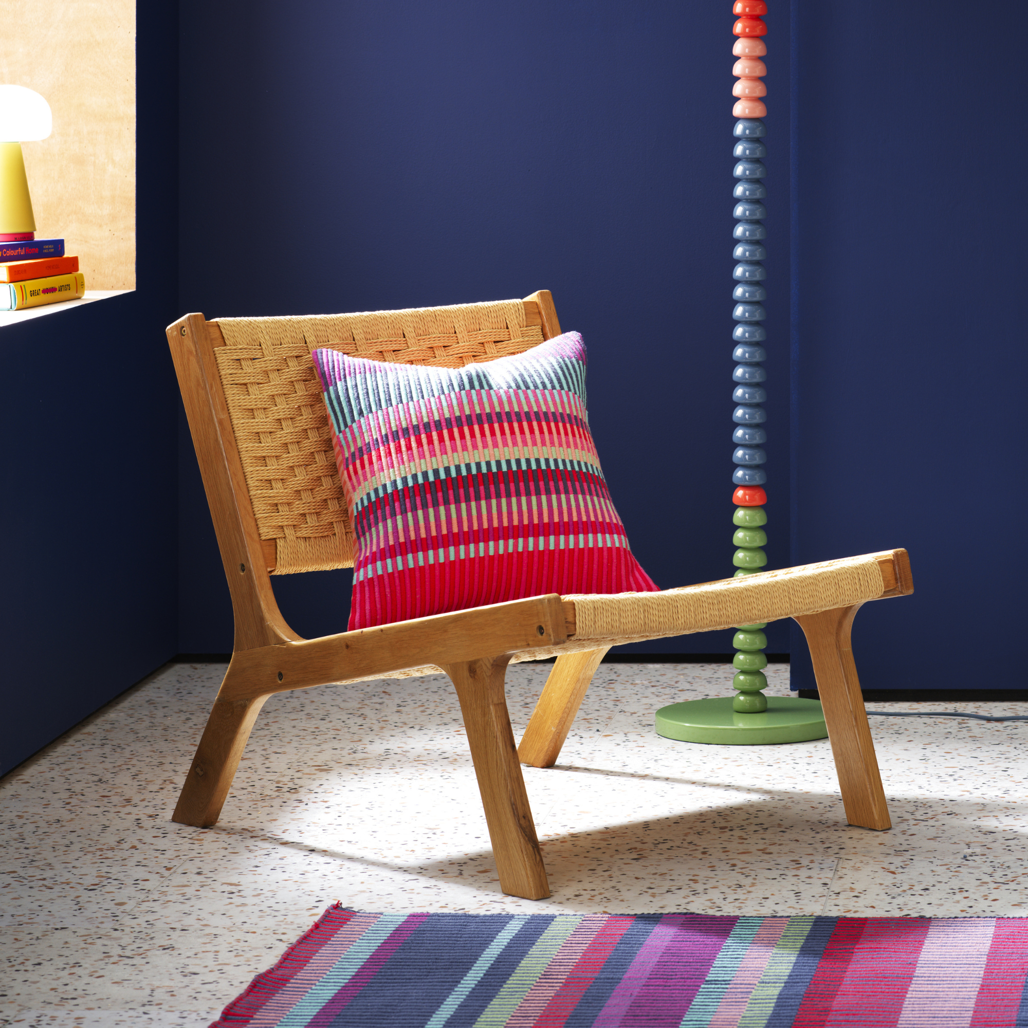 Buster Red Cushion on a wooden angled chair.