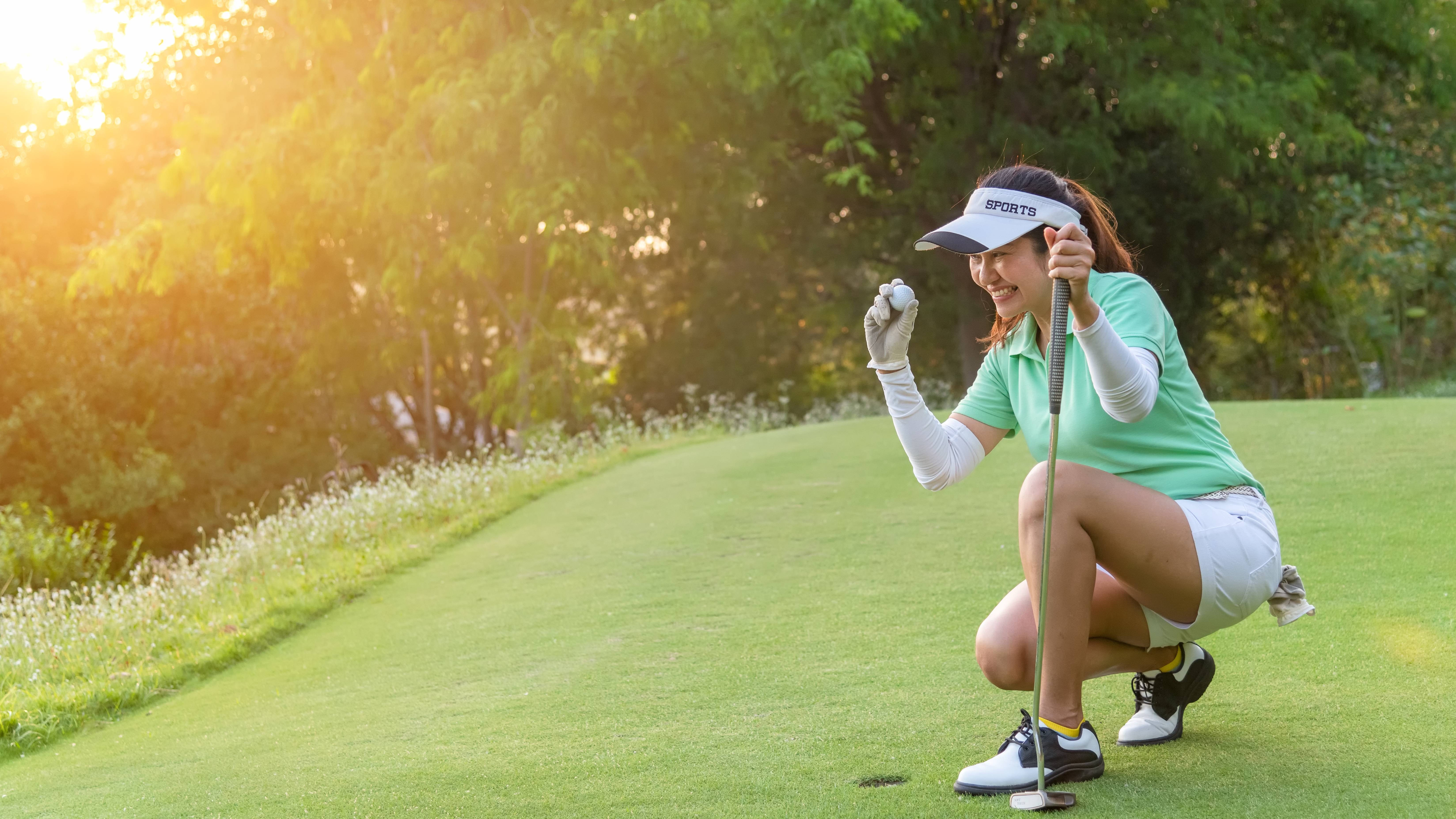Female golfer teeing up the ball and smiling