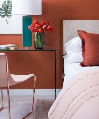 colors that go with light pink, terracotta and light pink bedroom, terracotta walls light pink chair and bedding, glass console/desk, artwork, jade table lamp
