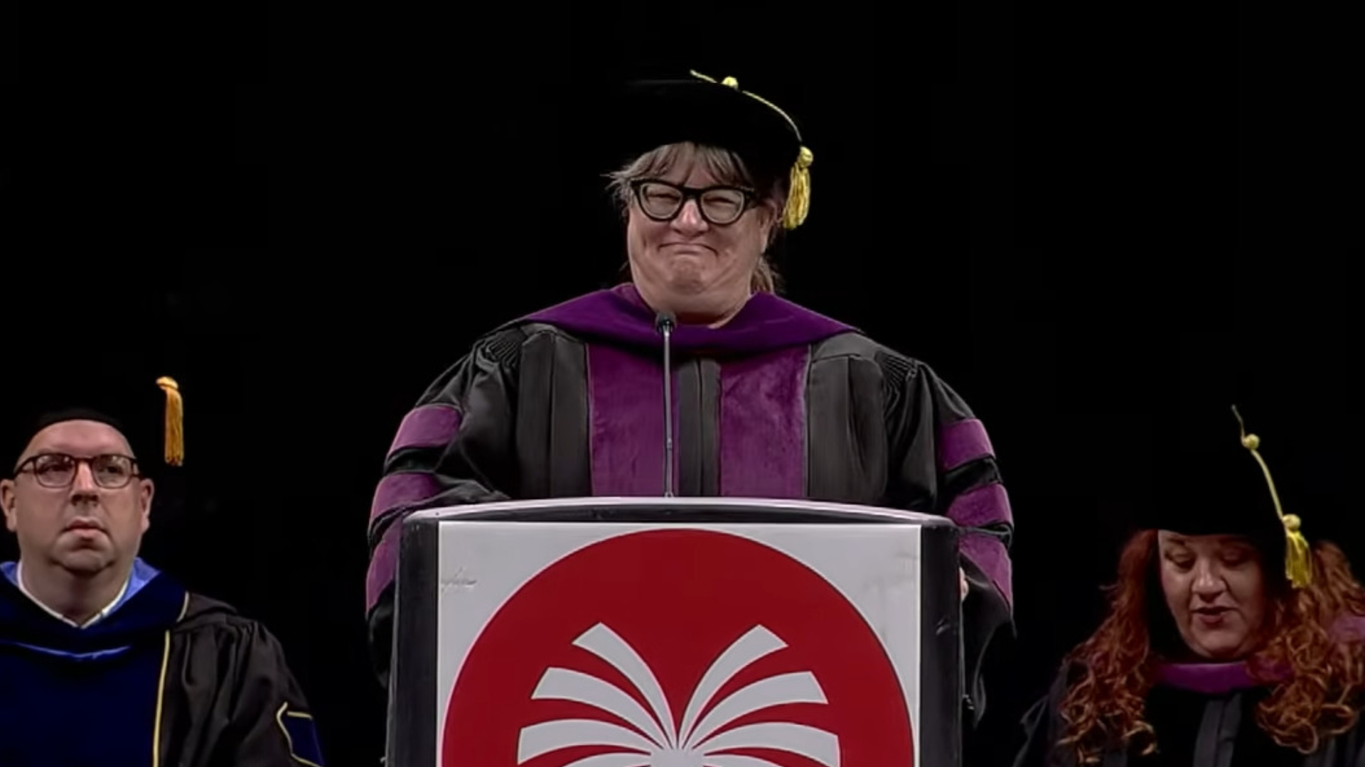 A public speaker at a US community college grimacing as they reveal to the students that their names were misread by the AI speaker system