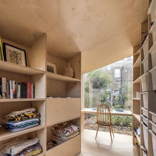 wooden storage shelves with books cloths wooden desk and chair