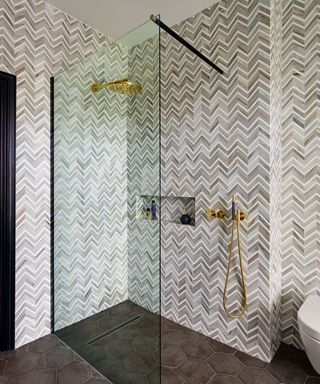 Gray bathroom, palette of gray tiles in a herringbone pattern, dark gray-brown tiled floor, metallic fittings