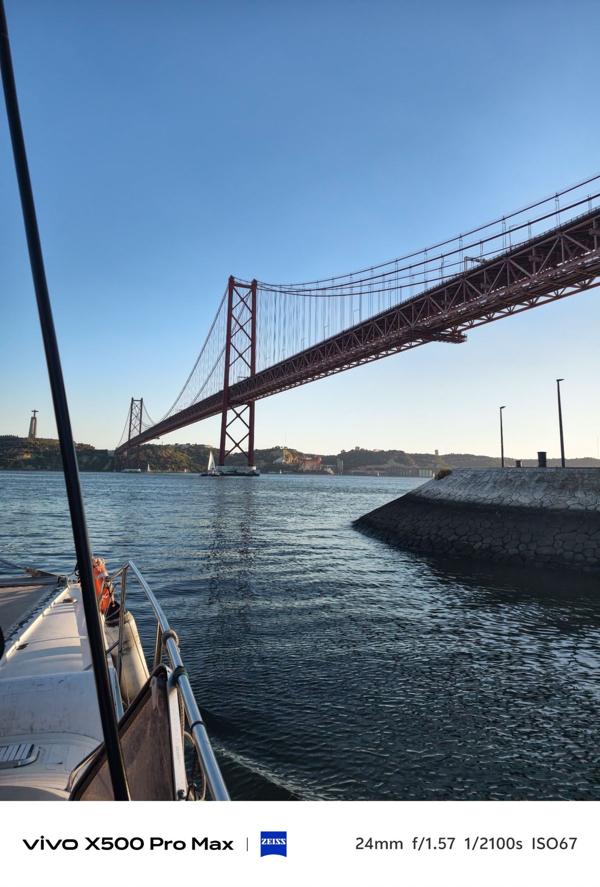 View from a boat toward Lisbon&rsquo;s red 25 de Abril suspension bridge spanning the Tagus River.