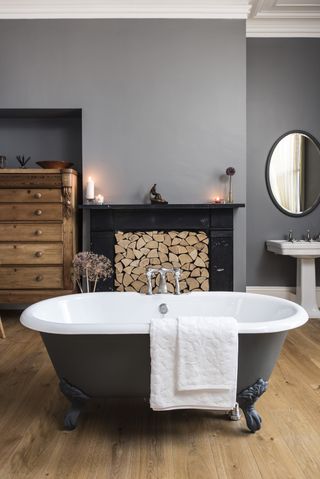 beautiful frestanding bath in centre of bathroom with large fire places filled with cut logs