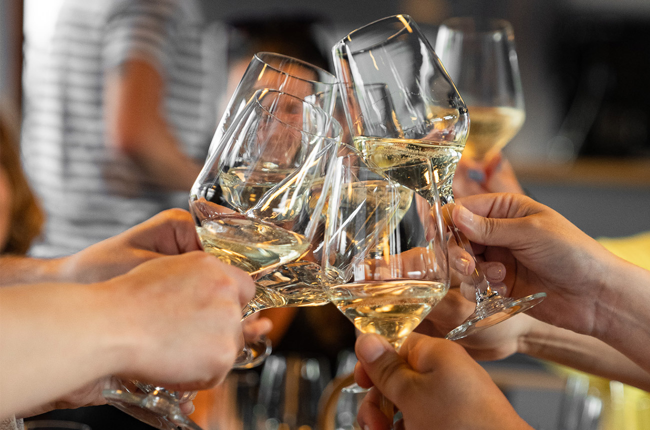 Hands with glasses of white wine &amp;ndash; doing a 'cheers'