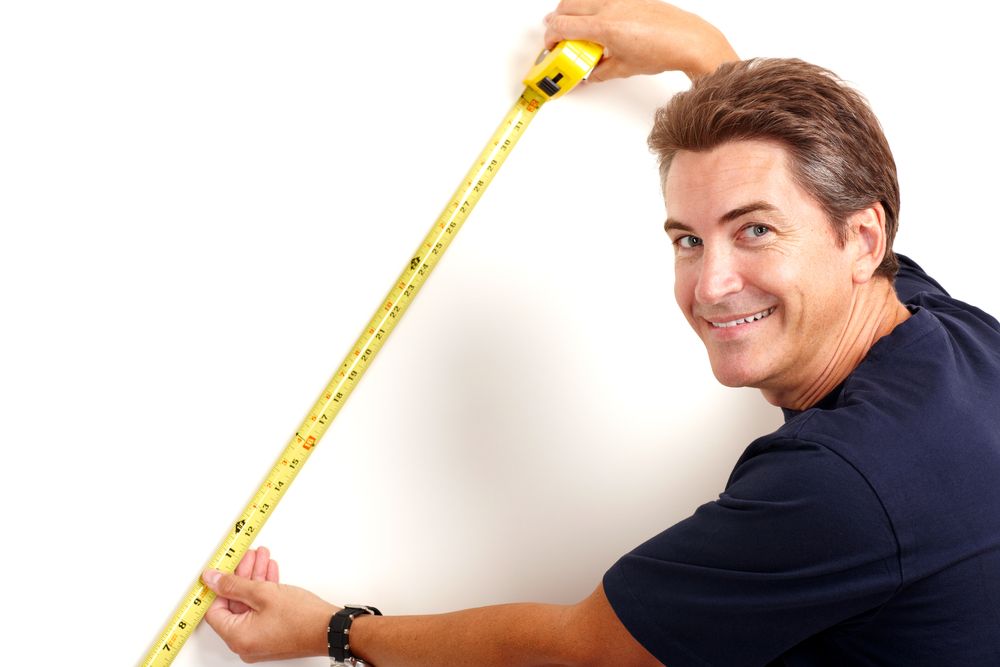 a man measuring a wall with measuring tape